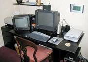 Personal computer and peripherals. From left to right: ink jet printer, TV (irrelevant), CRT monitor, broadband cable modem for the internet, flat bed scanner. The tower (CPU, hard drive, etc) can just be glimpsed at bottom right. The keyboard and mouse are wireless.